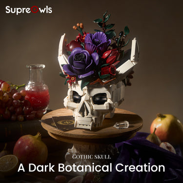 Gothic skull decor featuring a white skull crowned with purple and red flowers, displayed on a wooden stand beside fruit and glassware