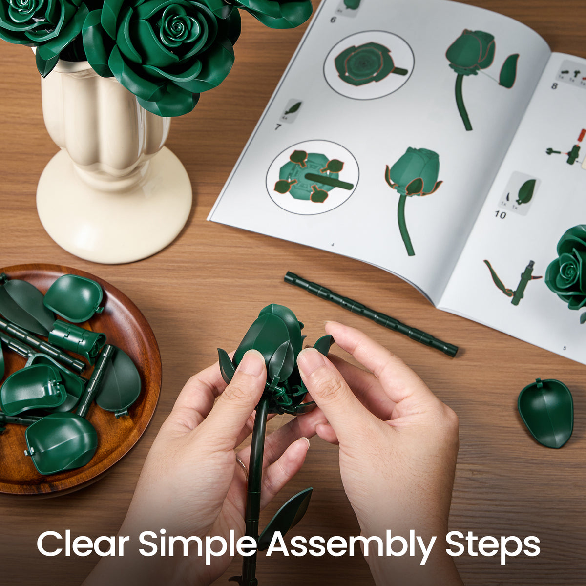 Green roses bouquet building block set assembly scene showing instruction guides, flower pieces, and hands connecting floral components on a tabletop.