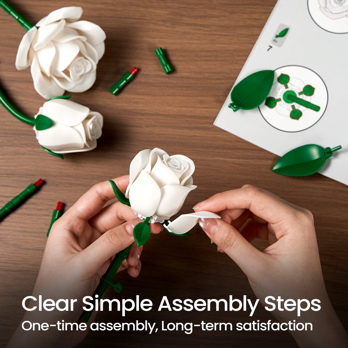 White roses bouquet building block set assembly process showing hands attaching flower pieces with loose components and instruction guides on a table.