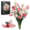 Standing pink-and-ivory tulip building bouquet with exposed stems on white, accompanied by its product box and several loose blossoms arranged at the lower left.