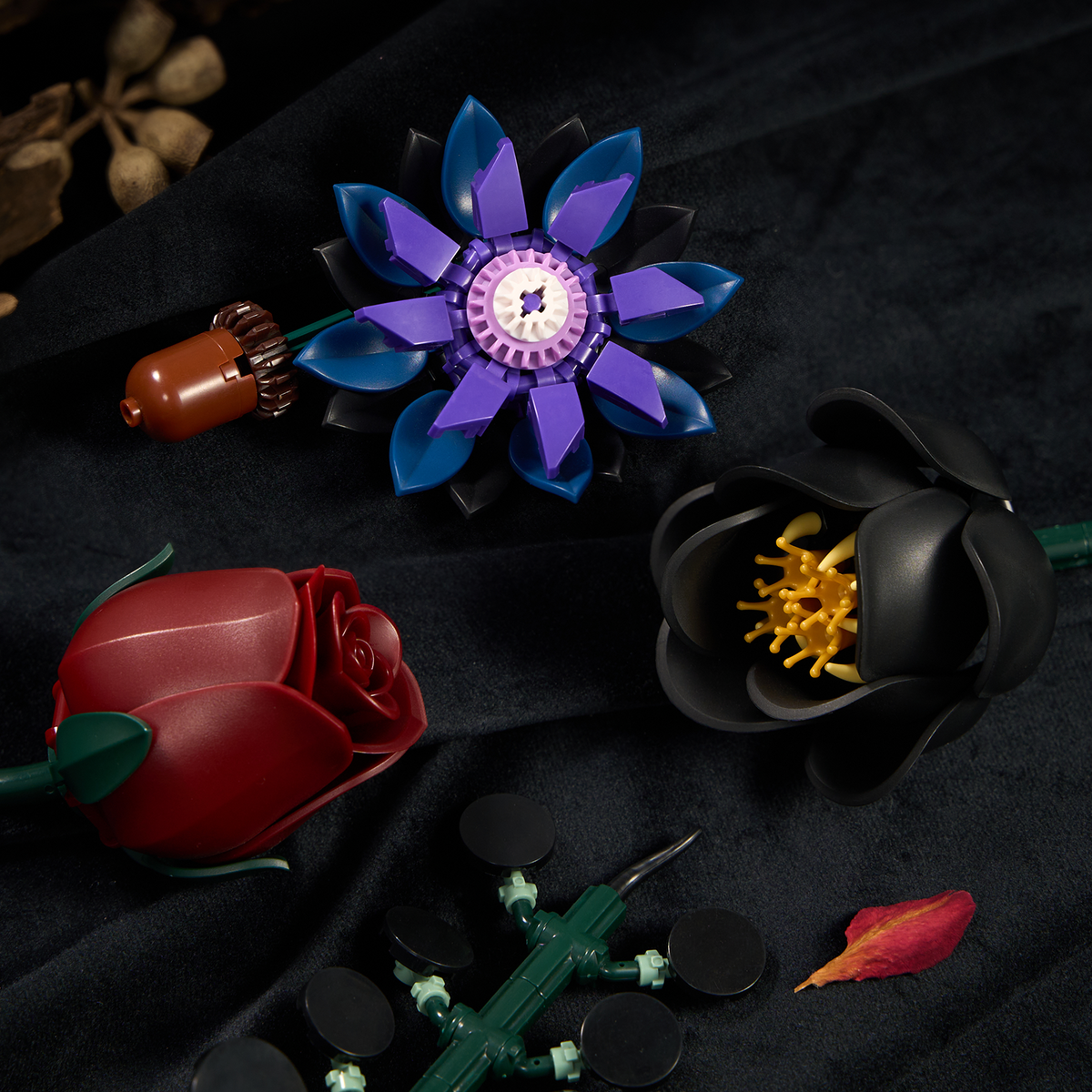 Close-up view of gothic flower building blocks featuring black and red roses, purple petals, and detailed floral components arranged on a dark surface.