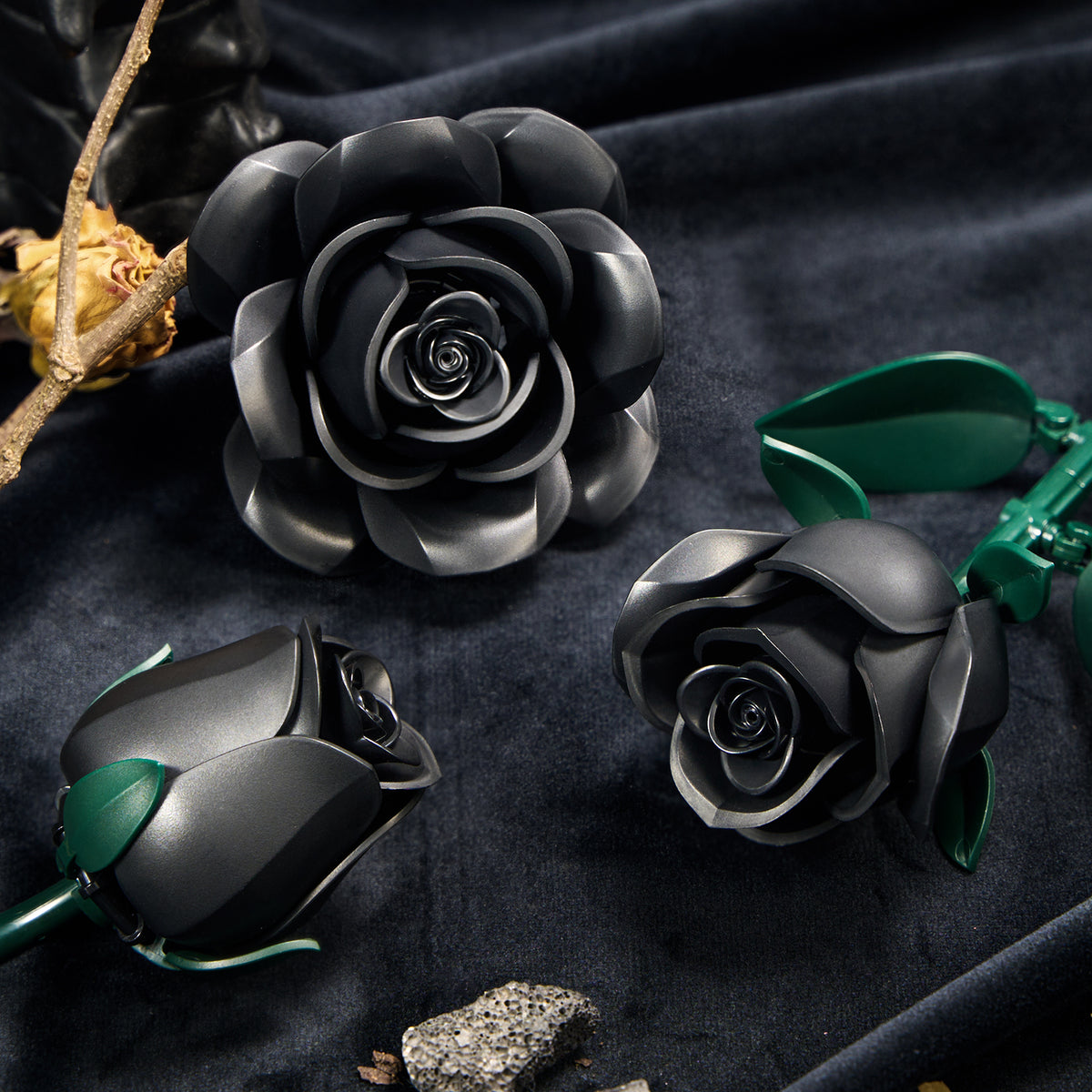Close-up view of black rose flowers with layered petals and green stems, arranged on a dark fabric surface to showcase the detailed structure and elegant design of the black rose bouquet.