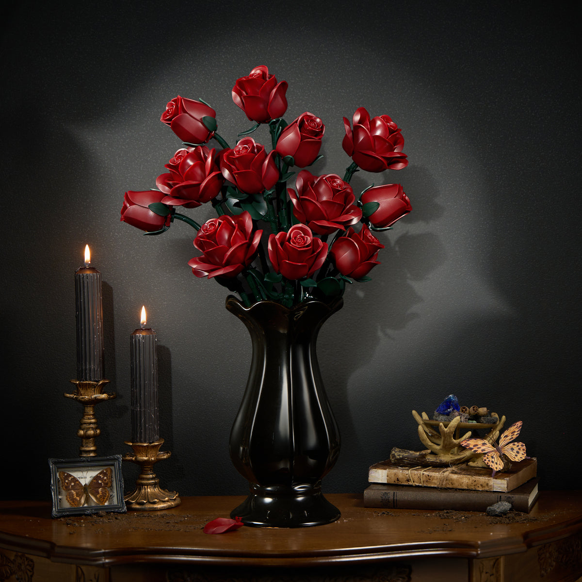 Burgundy rose building bouquet set displayed in a black vase on a wooden table, featuring deep red roses with green stems and leaves in an elegant dark interior setting with candles and decorative accents.