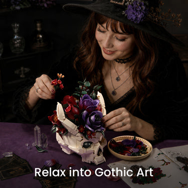 Woman assembling a Gothic Skull Floral Bouquet building set with purple and red flowers at a table in a dark interior