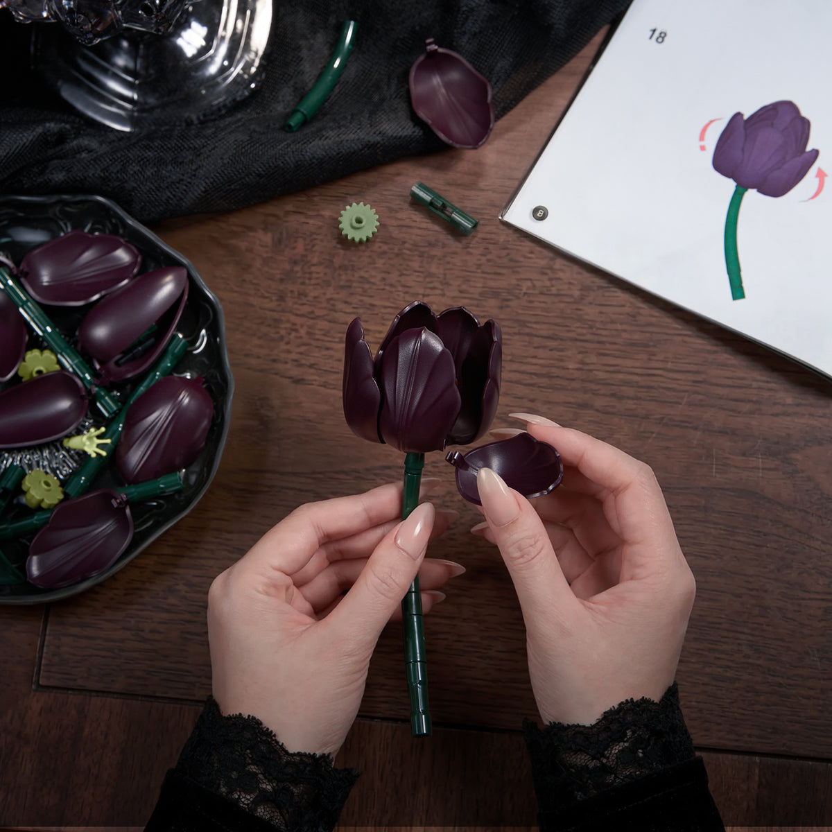 Tulip flower bouquet building block set showing a DIY assembly process with hands attaching dark purple petals and flower components to create a realistic botanical decoration.