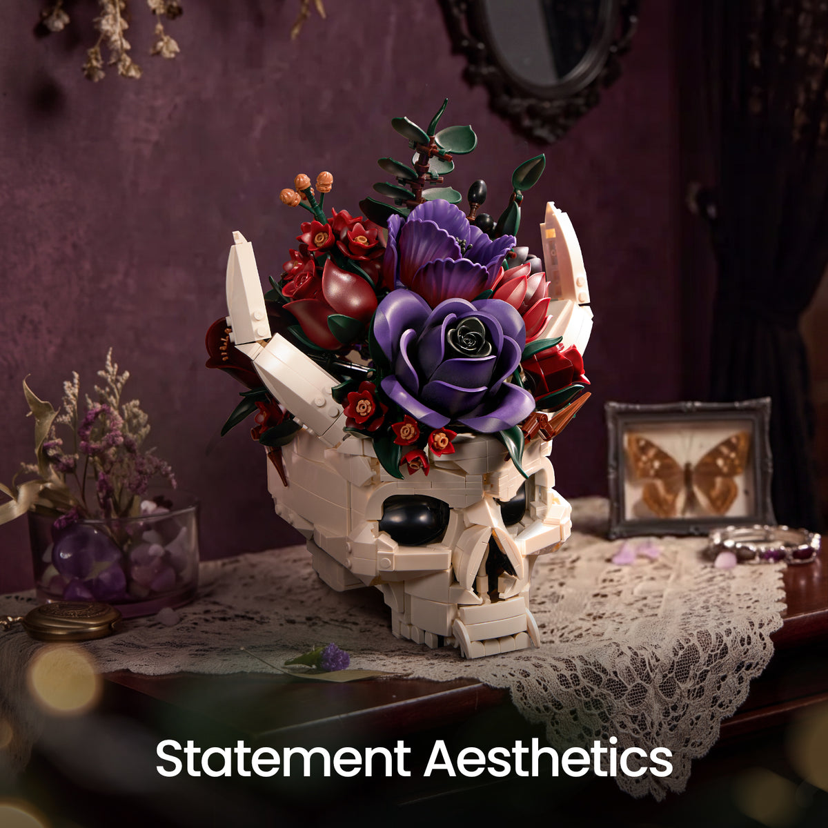 Gothic skull decor crowned with purple and red flowers, displayed on stacked books in a dark interior with candles and floral decorations