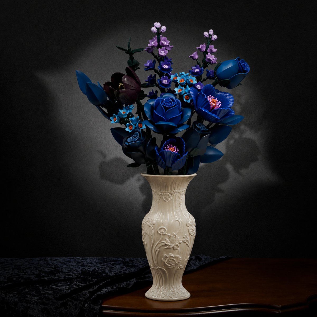 Blue flower bouquet building block set with deep blue roses, blue and purple flowers, displayed in an ornate cream vase on a wooden table against a dark background