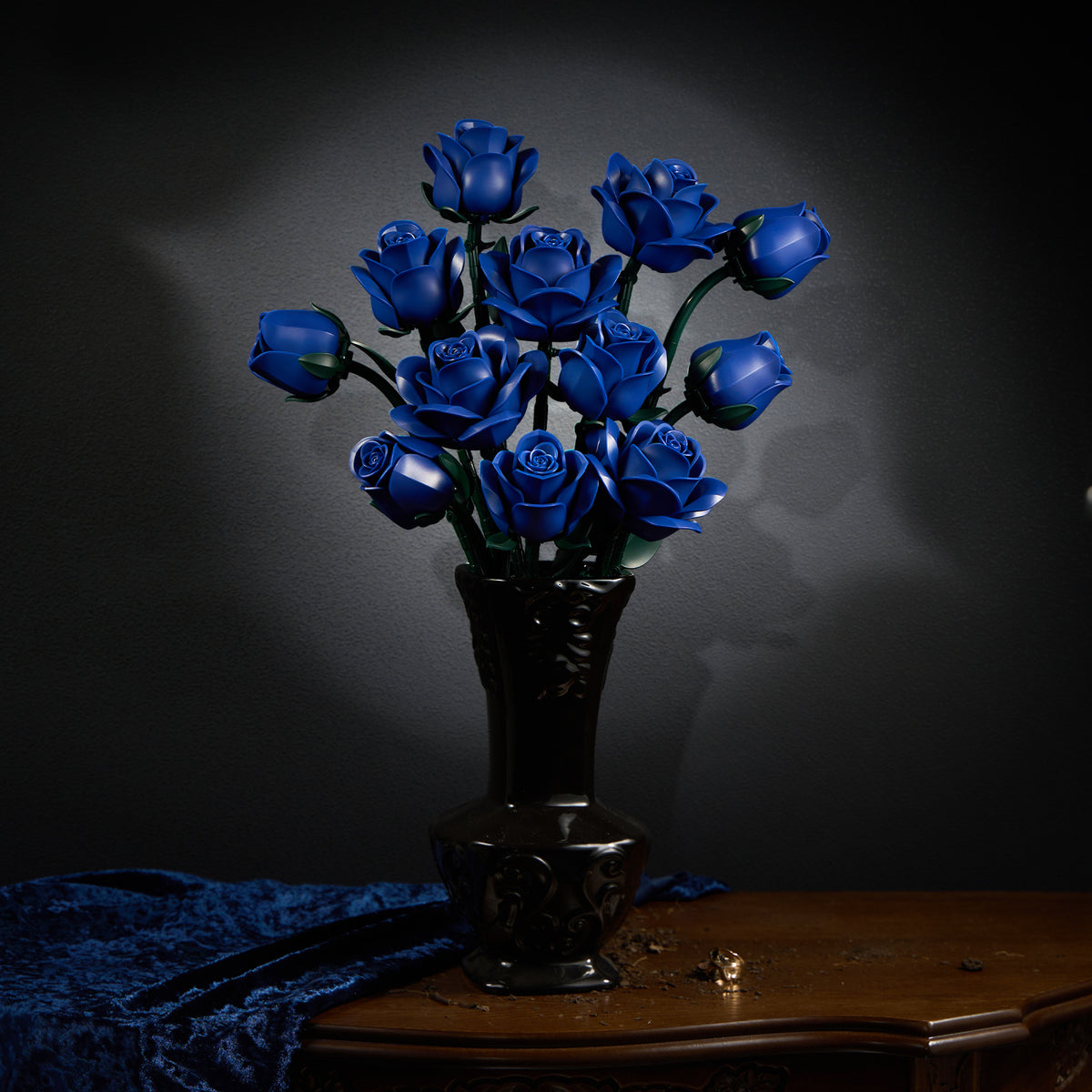A bouquet of deep blue roses arranged in a black vase, displayed on a wooden table against a dark background, creating an elegant and dramatic floral decor scene.